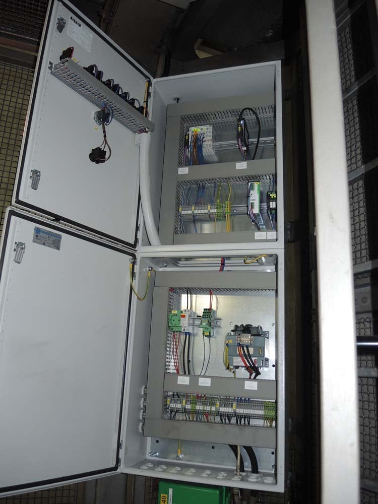 Offener Schaltschrank mit elektrischen Komponenten, Verkabelung und Sicherungselementen in einer industriellen Umgebung